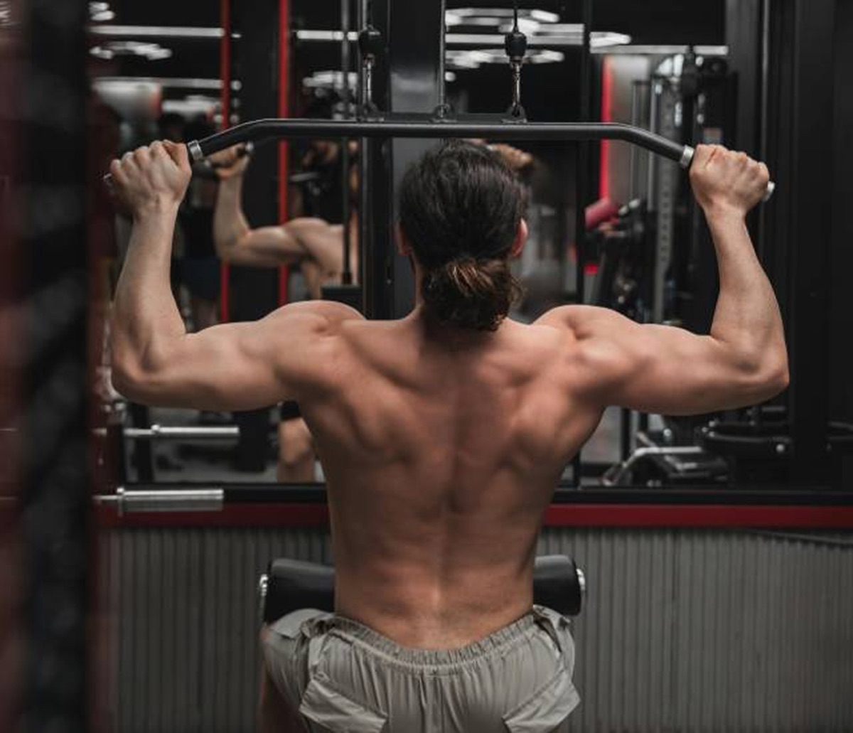 A lifter seen from behind pulling the bar down on a lat pulldown machine